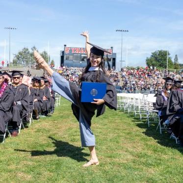 A graduate holding a diploma and doing a dance move