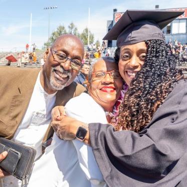 A graduate hugging her family 